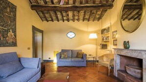 A cozy living room with a blue sofa, a red ottoman, a fireplace, and a bookshelf. - NAVONA PENTHOUSE APARTMENT WITH TERRACES (Roma)