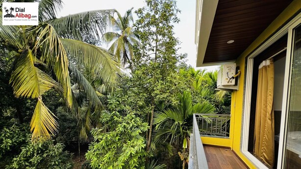 A balcony with a view of lush greenery and a building with a yellow exterior.