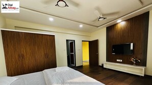 A hotel room with two beds, a TV, wooden wardrobe, and a bright hallway.