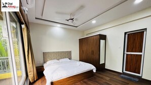 A bedroom with a bed, wooden flooring, a wardrobe, and a ceiling fan.