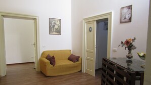 A living room with a yellow sofa, a wooden coffee table, and a vase with flowers. - The Courtyard Room Fishing (Scicli)