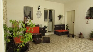 A cozy patio area with a wooden bench, a small table, and potted plants. - The Courtyard Room Fishing (Scicli)