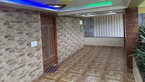 A hallway with patterned walls, a wooden door, and a herringbone floor. - Hotel Blue Moon (Gadag-Betageri)