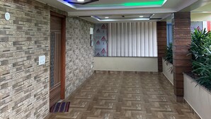 A hotel lobby with a herringbone patterned floor, a decorative ceiling with recessed lighting, and a reception area with a window and blinds. - Hotel Blue Moon (Gadag-Betageri)