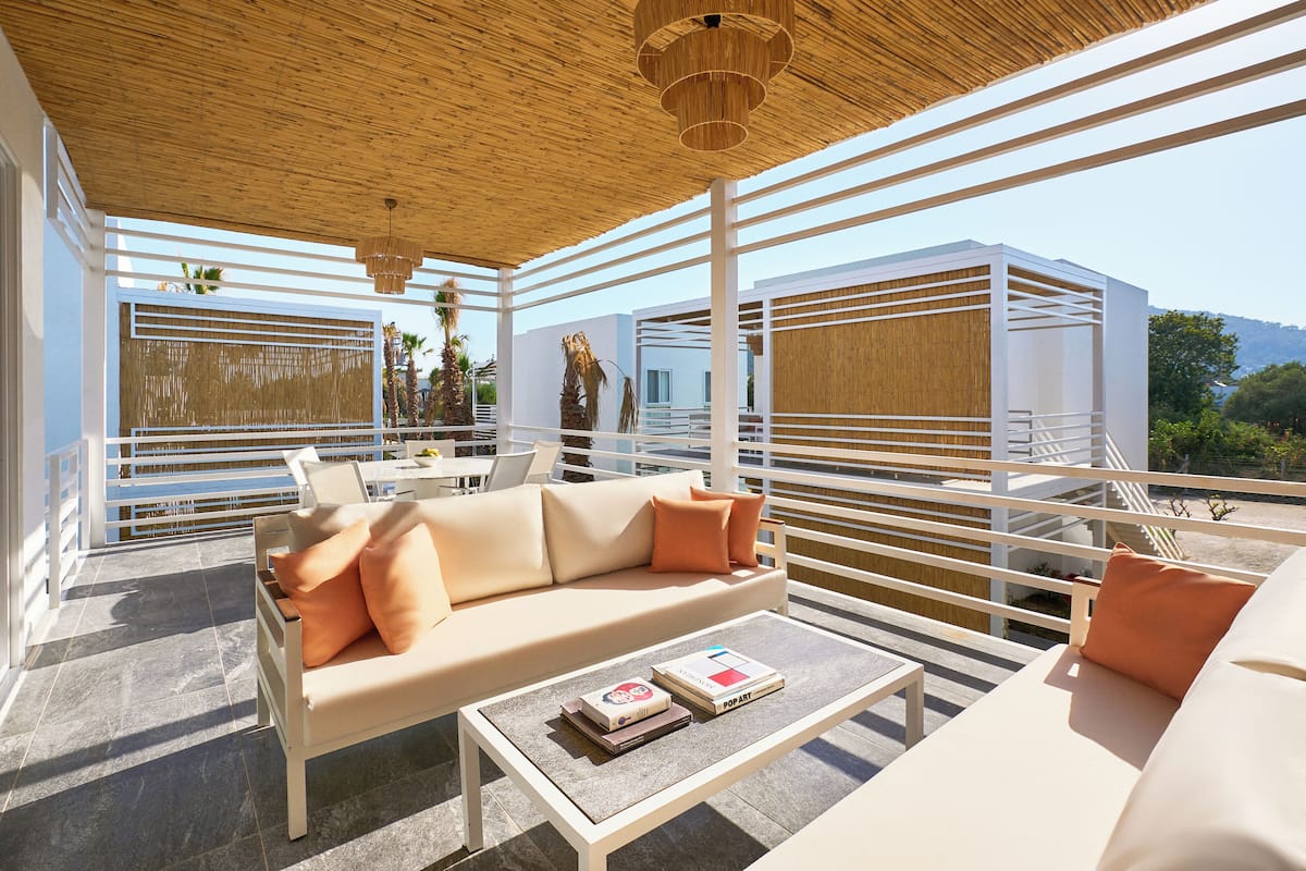 A modern outdoor lounge area with a sofa, coffee table, and a view of the sea.