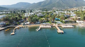 A coastal resort with a marina, sun loungers, and a mountain backdrop. - Flamm Residences (Bodrum)