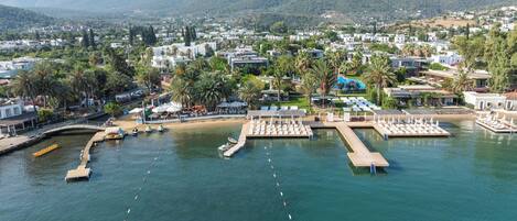 A coastal resort with a marina, sun loungers, and a mountain backdrop.