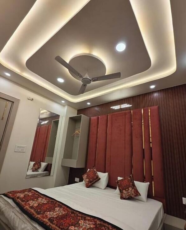 A modern hotel room with a large bed, a ceiling fan, and a mirror.