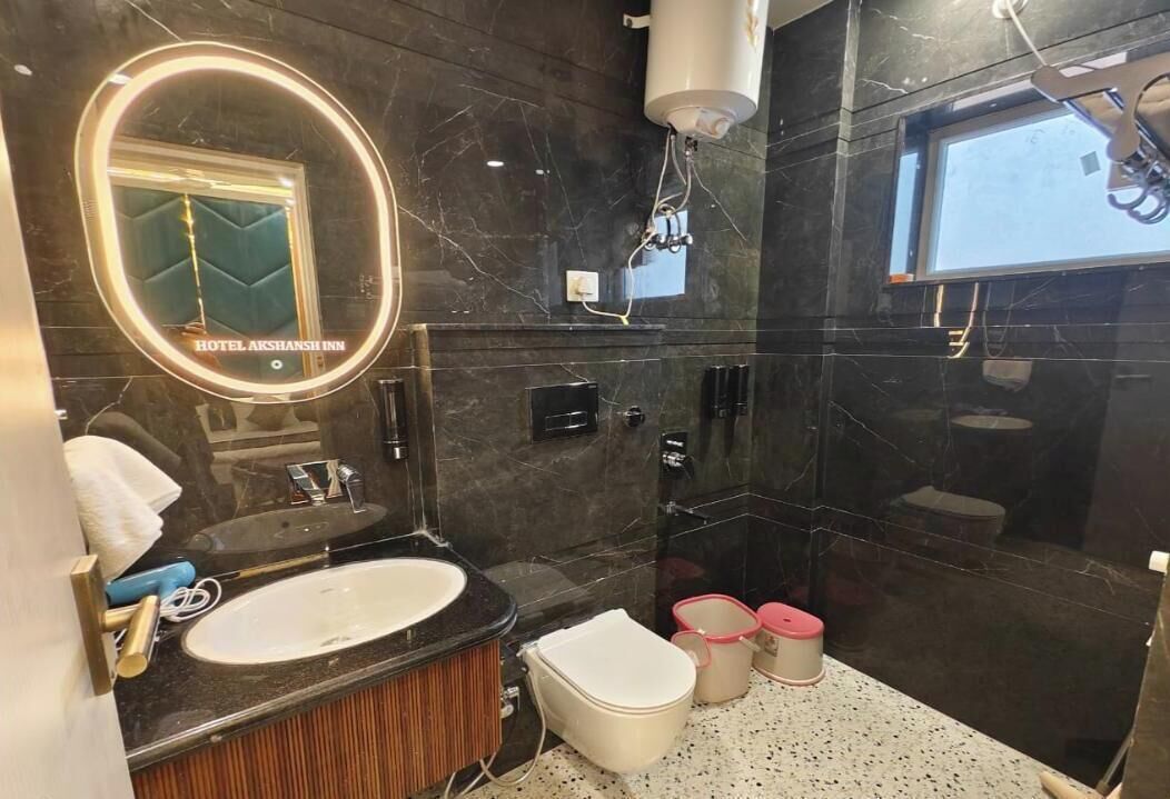 Een moderne badkamer met een zwart marmeren wastafelmeubel, een witte wastafel, een toilet en een douchehoek.