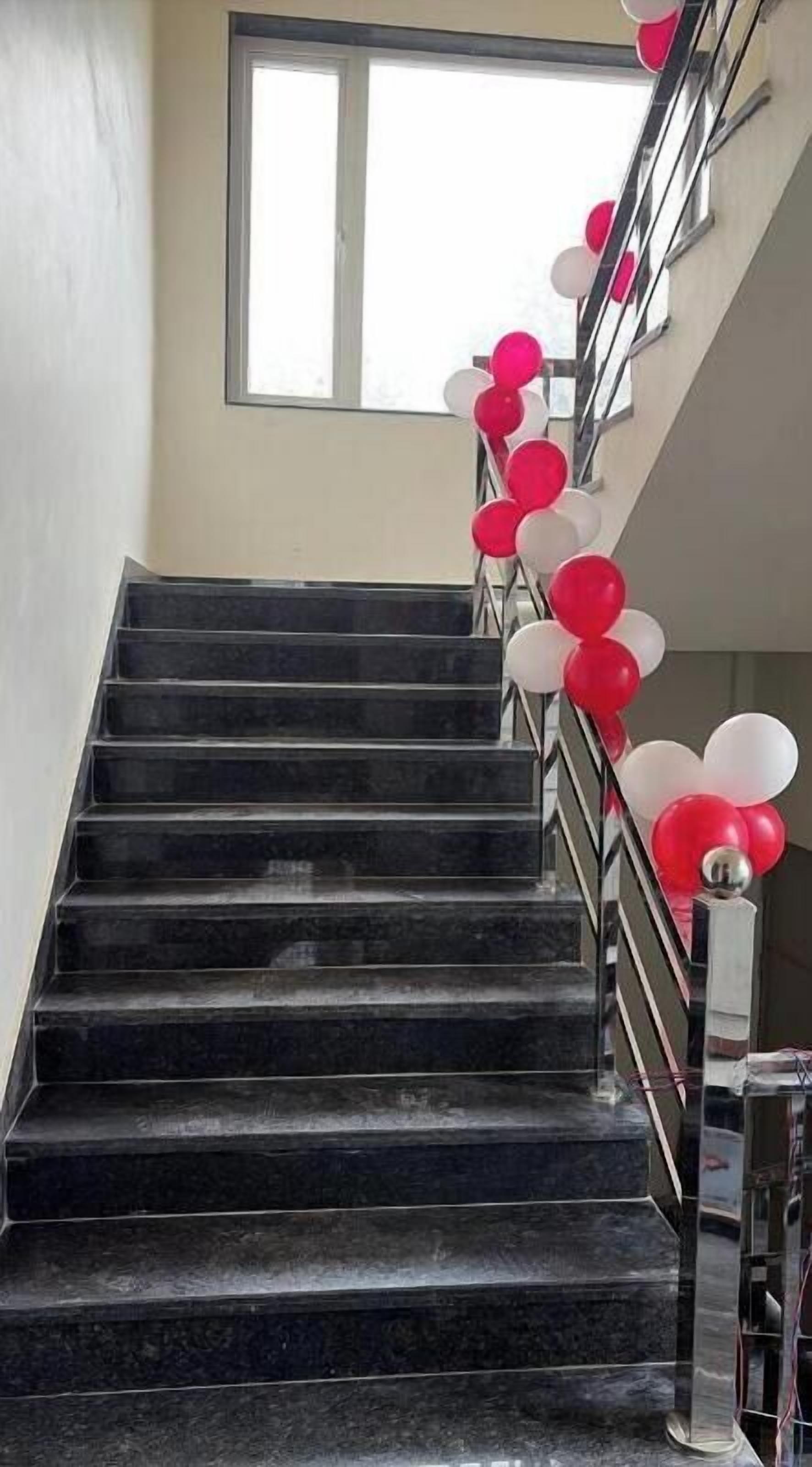A staircase with black steps and a metal railing, decorated with red and white balloons.