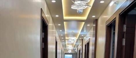 A long, well-lit hallway with a reflective floor and doors on both sides.