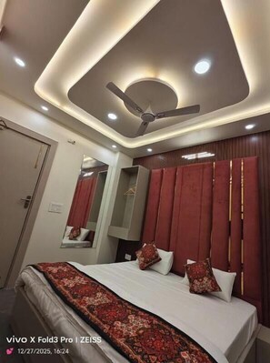 A modern hotel room with a bed, a ceiling fan, recessed lighting, and a large mirror.