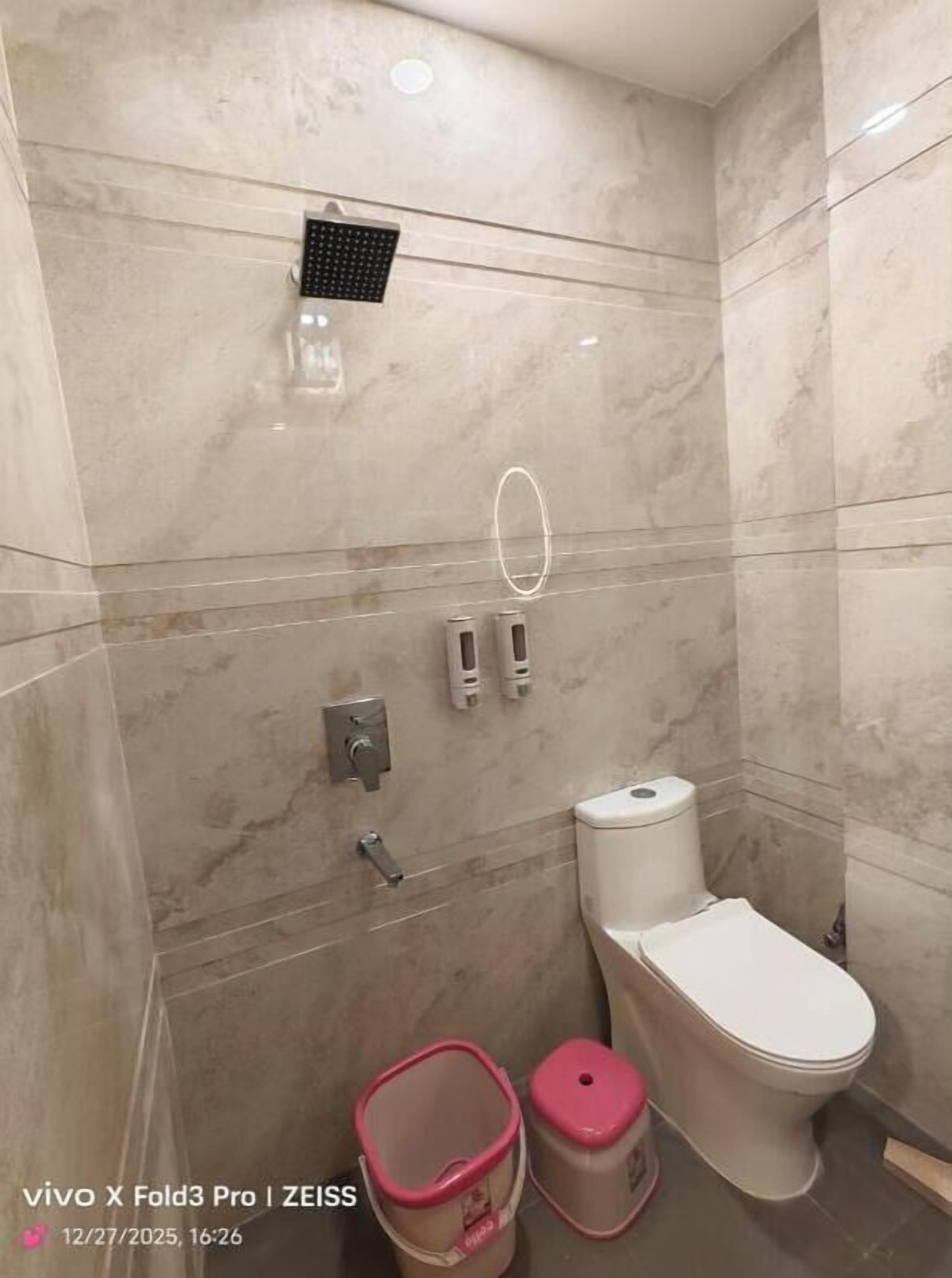 Un baño con inodoro, bidé y un cubo de basura.