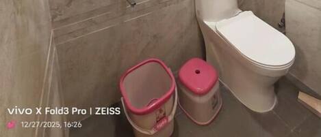 Un baño con inodoro, bidé y un cubo de basura.
