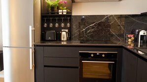 Een moderne keuken met een ingebouwde koelkast, oven en broodrooster. Er staan potplanten op het aanrecht en een wijnrek erboven.