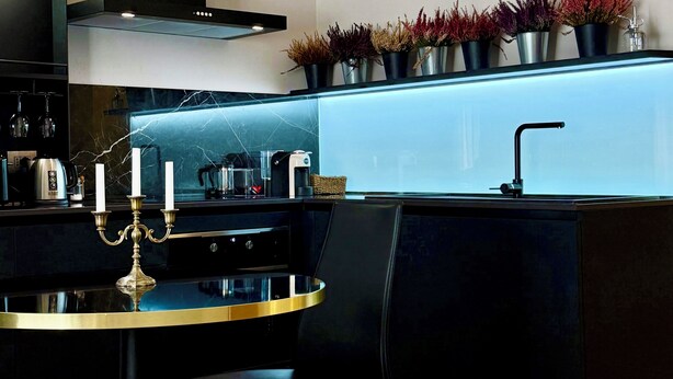 Een moderne keuken met een zwart aanrecht, een ronde tafel en een stoel.