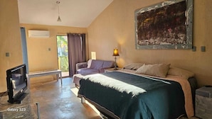 Un dormitorio con cama, sofá, televisión y aire acondicionado.