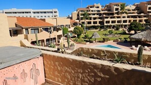 Un hotel de varios pisos, piscina exterior y cactus.