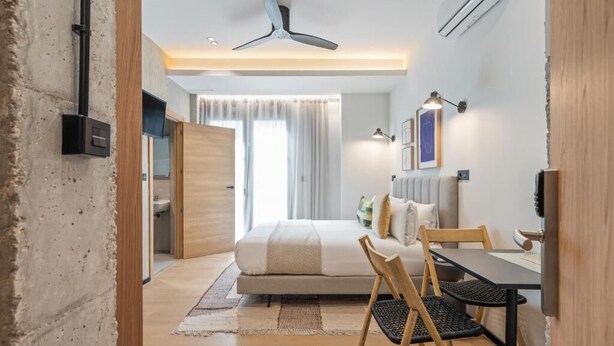 A modern hotel room with a bed, a desk, and a chair. There is a ceiling fan, a window with curtains, and a wall-mounted TV. - Dobo Madrid Moncayo (Madrid)