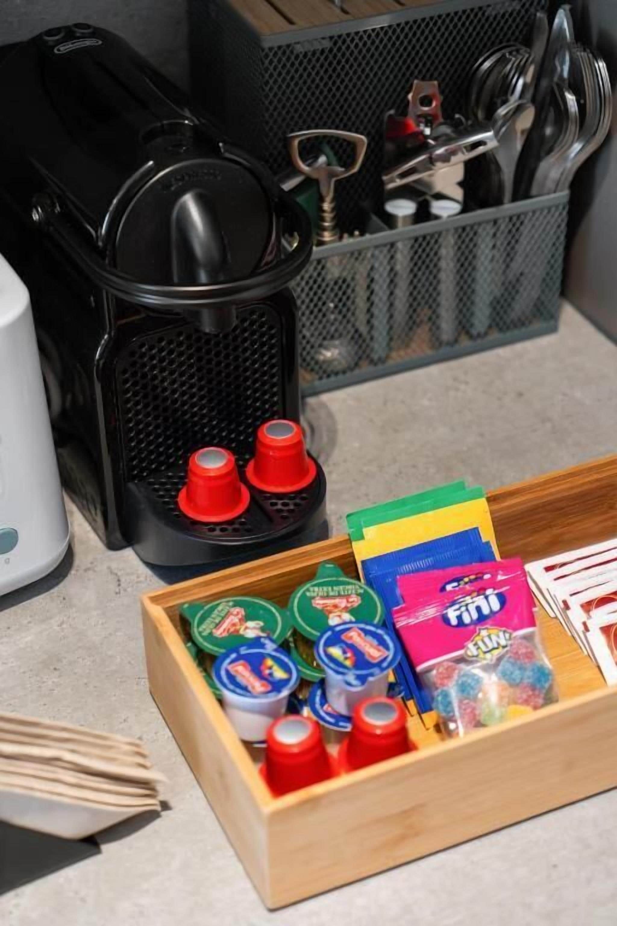 Una encimera de cocina con una cafetera, un especiero y una caja de madera con varios alimentos.