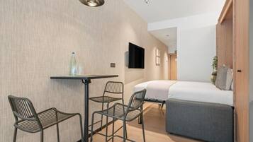 Una habitación de hotel moderna con una cama, una mesita y dos sillas.