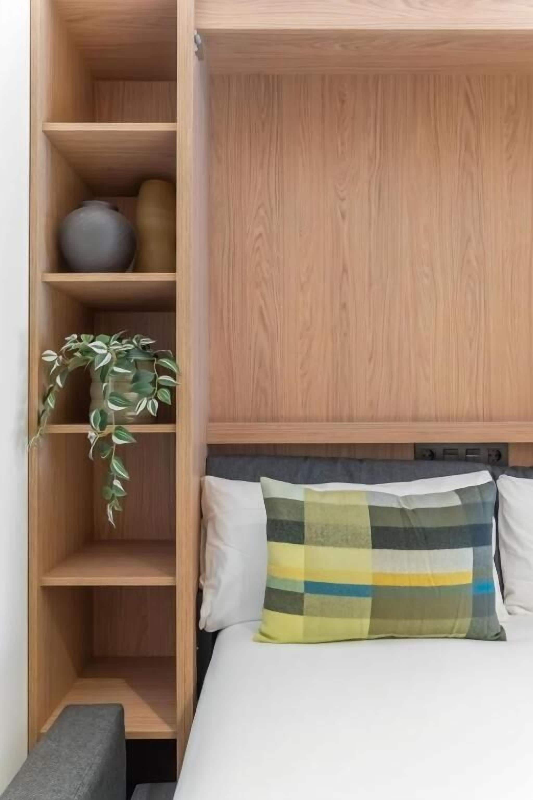 Un dormitorio con una cama, un armario de madera y una planta.