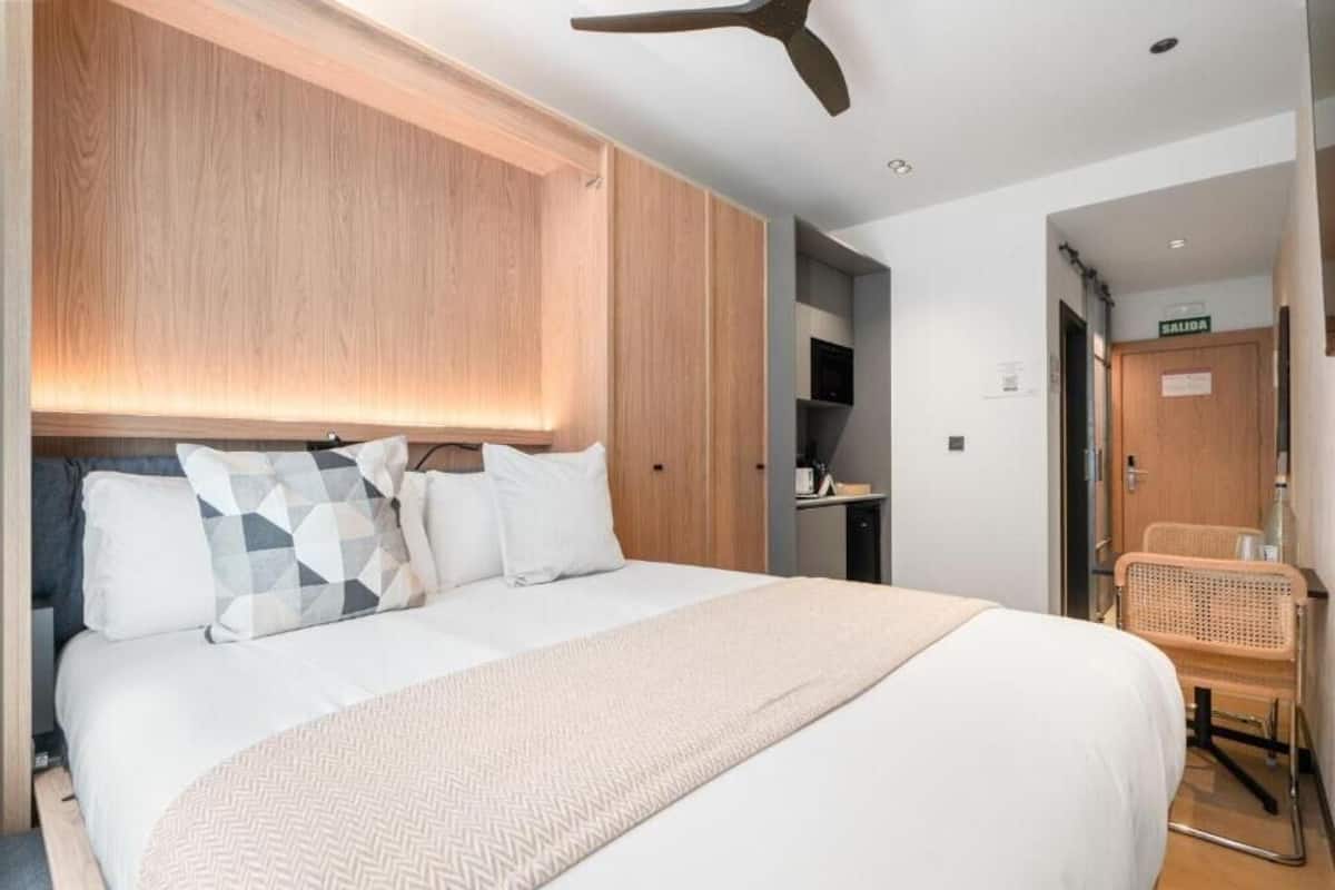 A hotel room with a large bed, wooden headboard, and a ceiling fan.