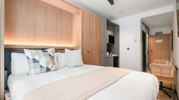 Una habitación de hotel con una cama grande, cabecero de madera y un ventilador de techo.