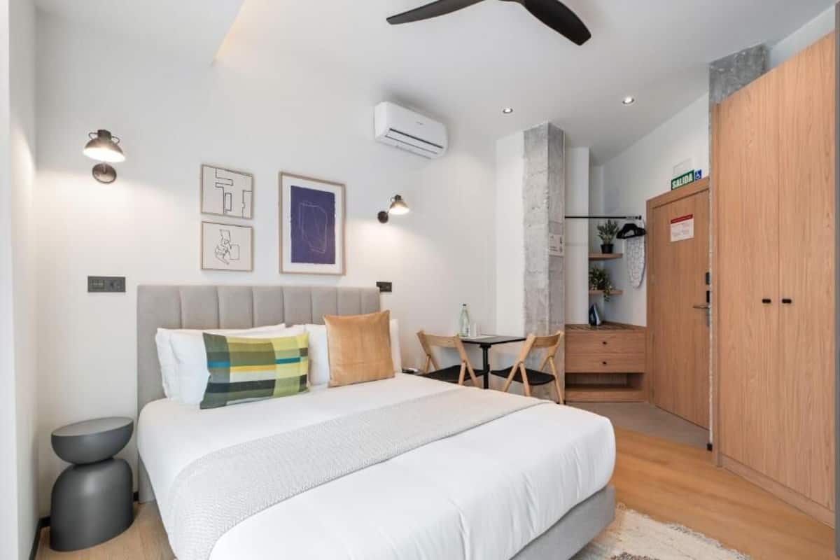 A modern bedroom with a large bed, bedside tables, a desk, and a wardrobe.