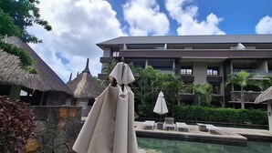 Ein Resort mit Pool, Liegestühlen und strohgedeckten Gebäuden.