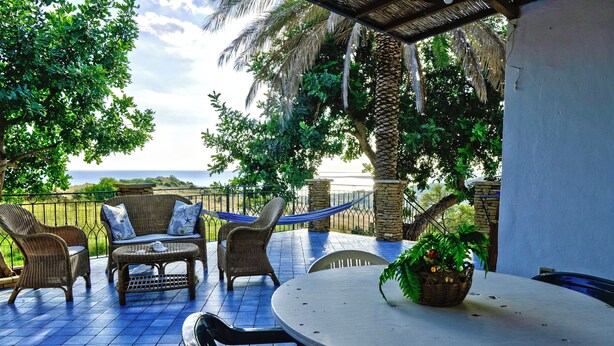 An outdoor patio with wicker furniture, a round table, and a hammock. - Monterotondo Holiday Home for 6 - with Pool, Nature and Close to the Beach (Sciacca)