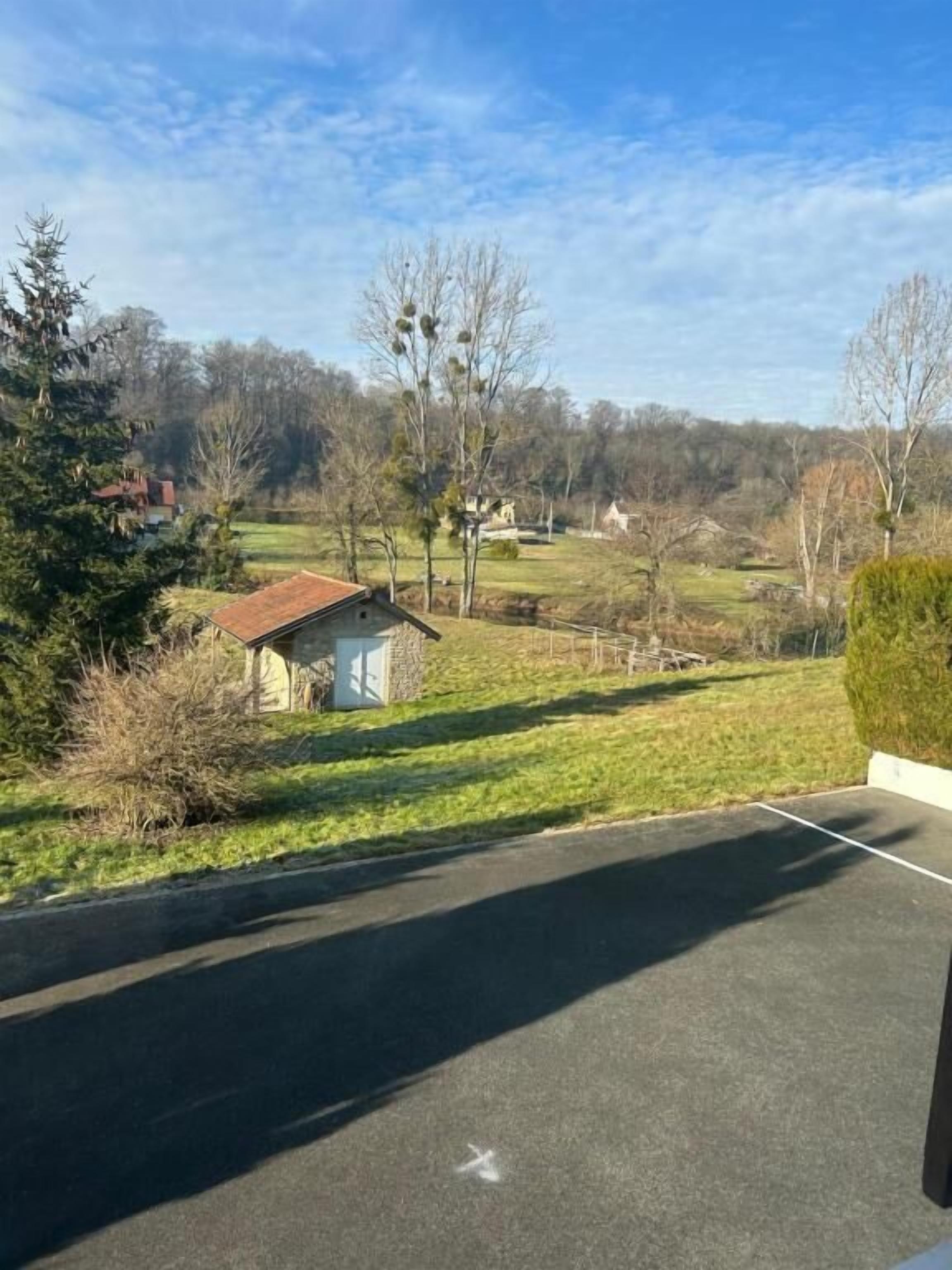 A parking area with a small shed and a grassy field in the background.