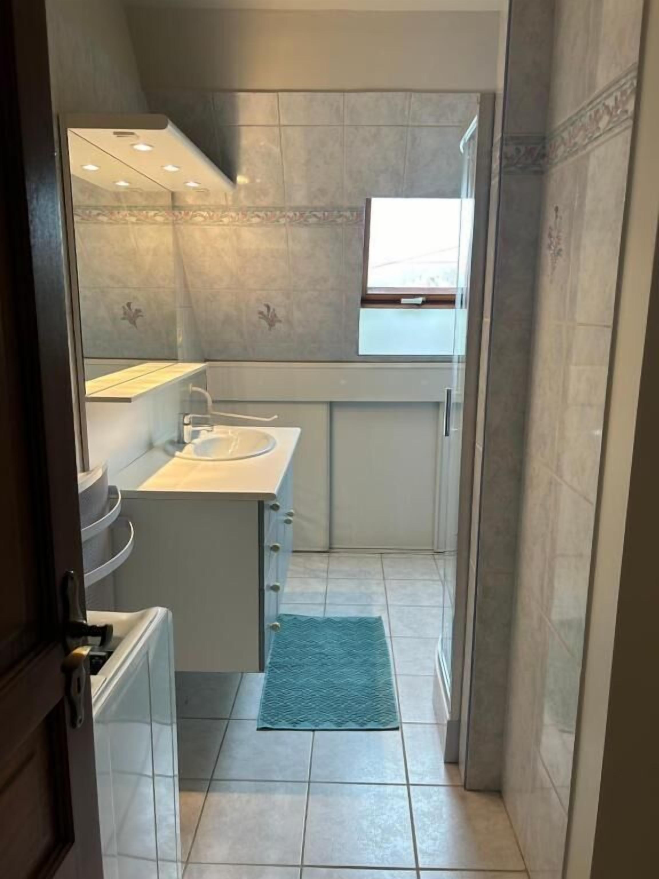 Ein kleines Badezimmer mit Waschbecken, Spiegel und Duschbereich.