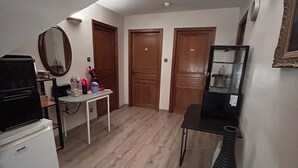 A compact kitchen with a refrigerator, a coffee machine, and a small table with various items. There are wooden doors and a mirror on the wall. - Les Bords de la Lizaine (Hericourt)