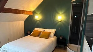 A bedroom with a bed, two nightstands, a curved shower, and a wooden ceiling beam. - Les Bords de la Lizaine (Hericourt)