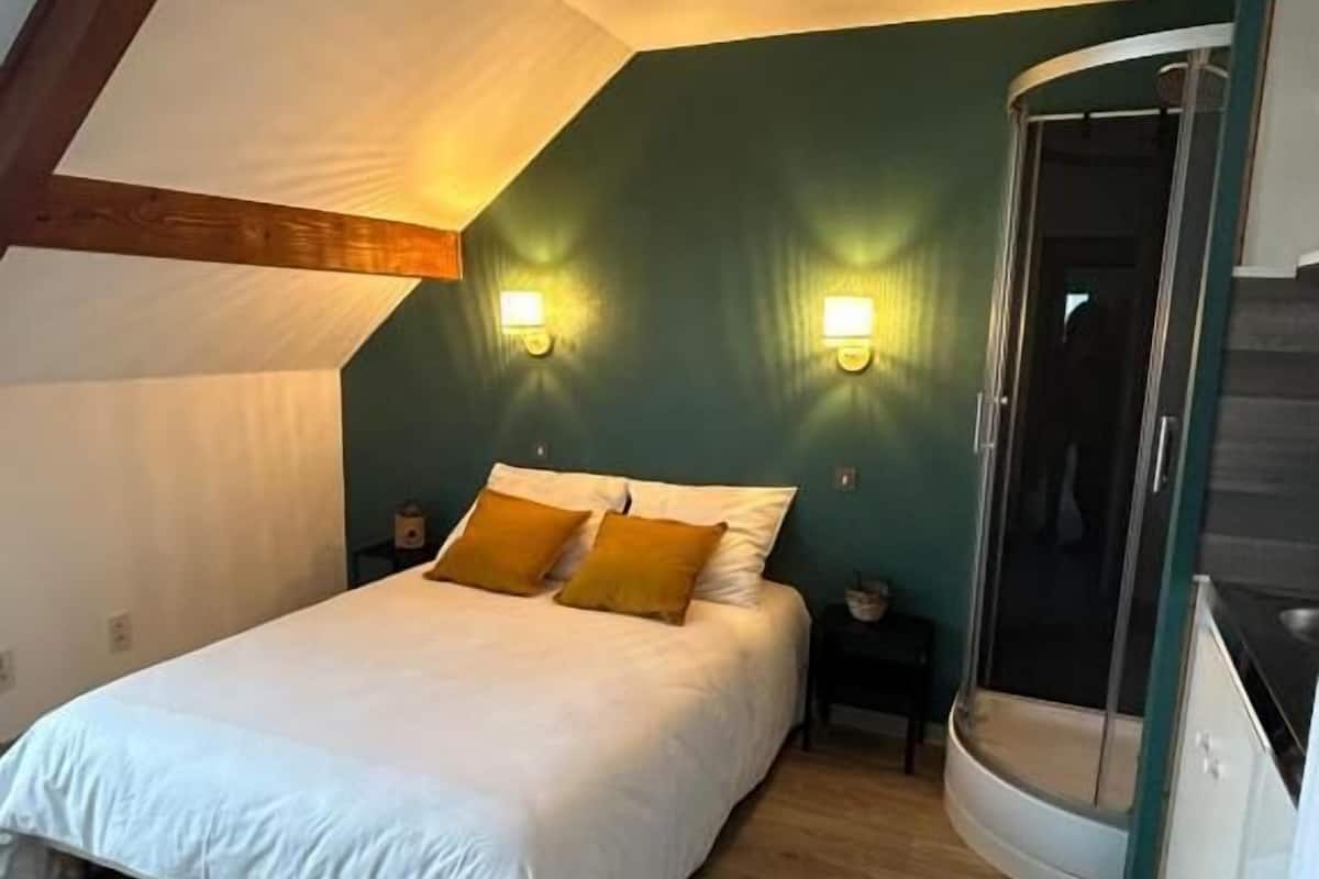 Ein Schlafzimmer mit einem Bett, zwei Nachttischen, einer Duschkabine mit Bogenform und einem Holzbalken an der Decke.