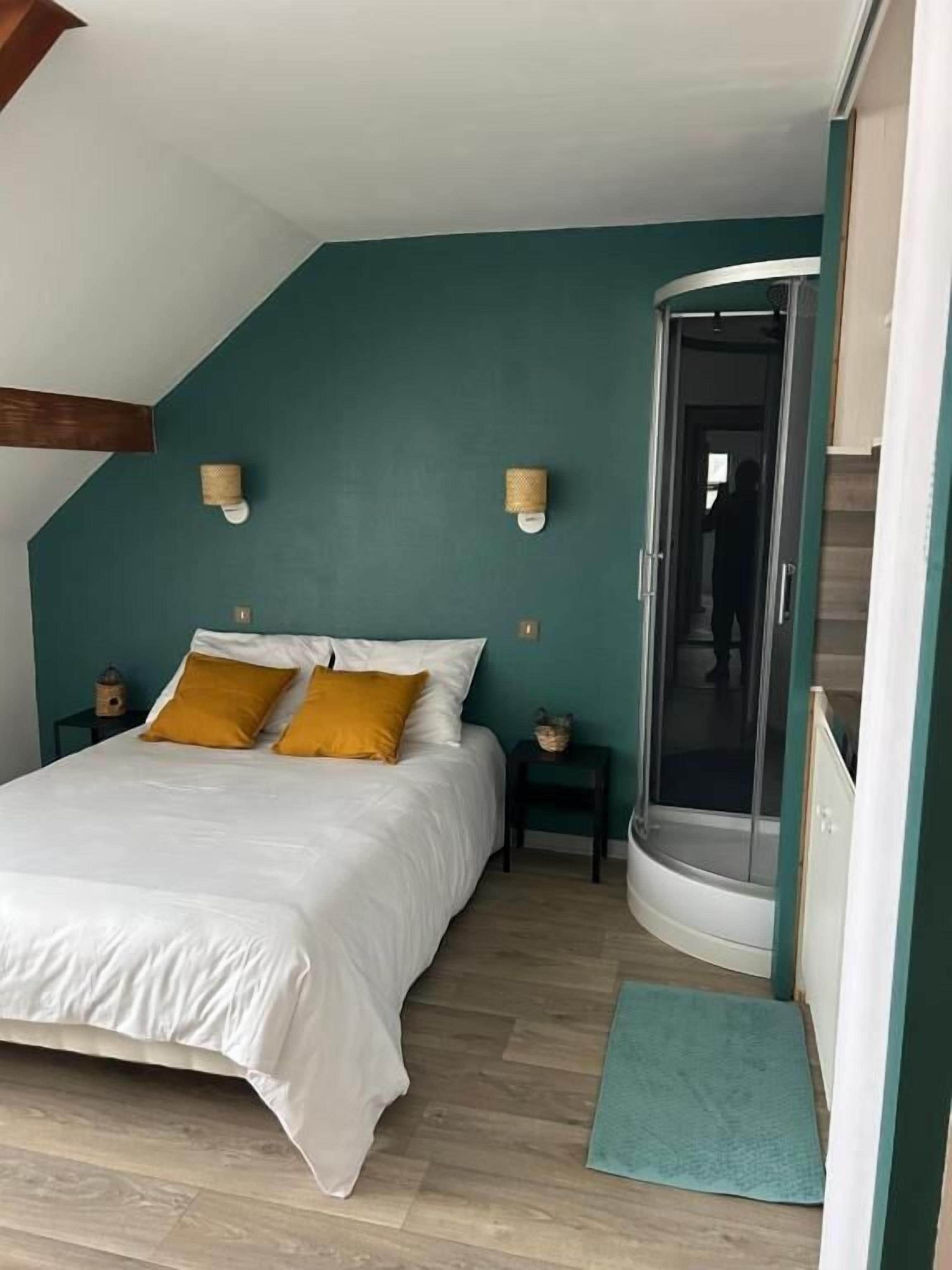 Une chambre à coucher comprenant un lit, deux tables de chevet, un dressing et une douche.
