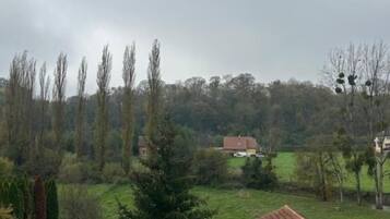 A rural landscape with a stone building, a fenced area, and a variety of trees.