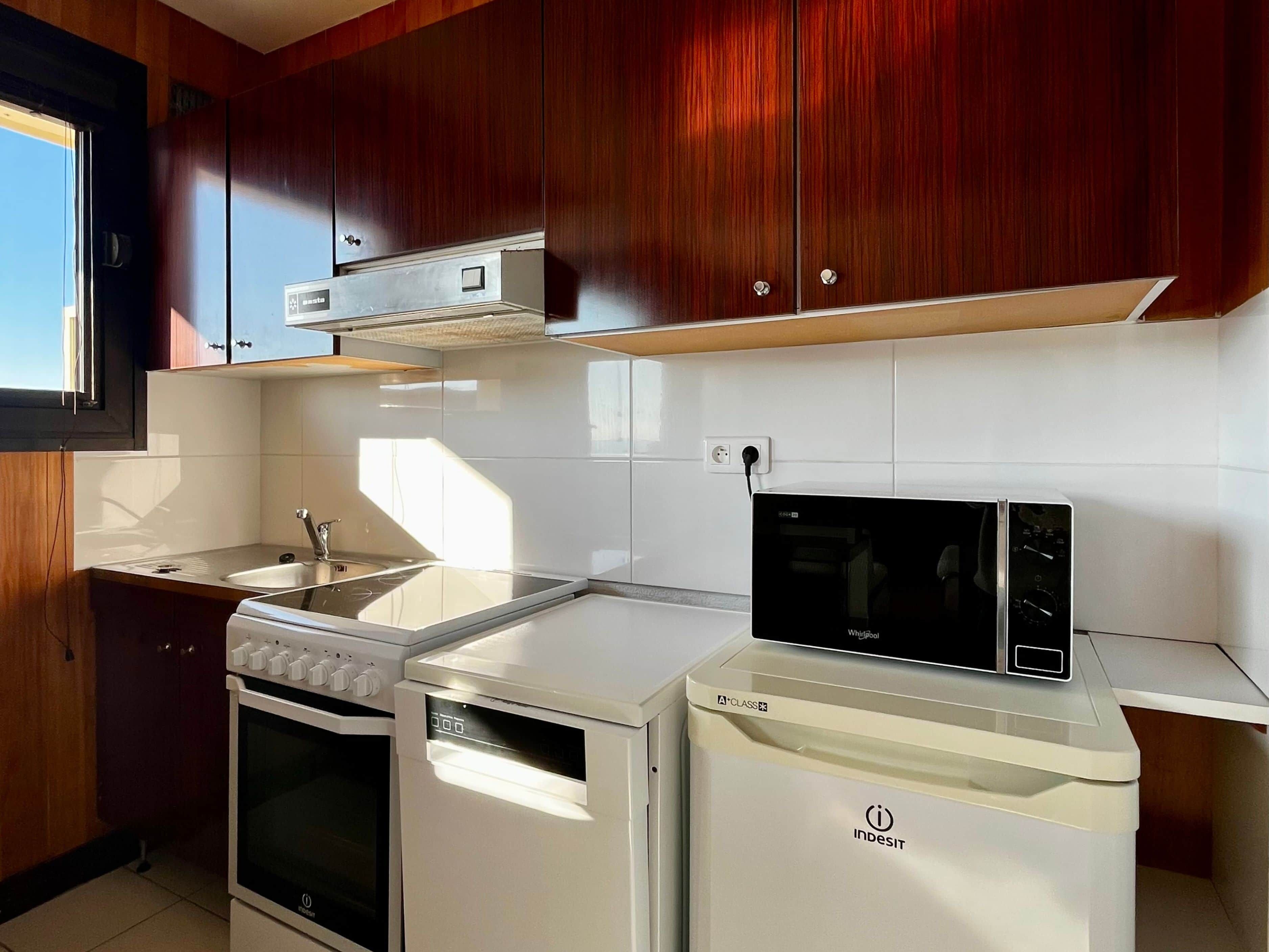 A modern kitchen with wooden cabinets, a built-in oven, a dishwasher, and a microwave.