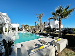 A pool area with lounge chairs, palm trees, and modern architecture. - Villa Lumina A Luminous Private Retreat With Pool & Fireplace in Hammamet (Bouficha)