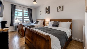 A bedroom with two beds, a view of the city, and a wooden floor. - Double room river view (Québec)