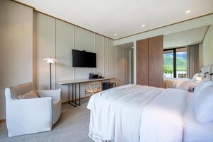 Habitación de hotel moderna con una cama grande, un escritorio con televisor de pantalla plana, una silla y vistas al exterior.