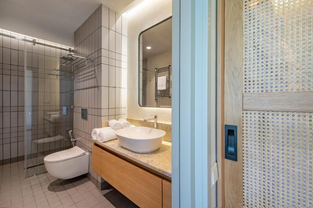 A modern bathroom with a glass-enclosed shower, a white sink, and a wooden vanity.
