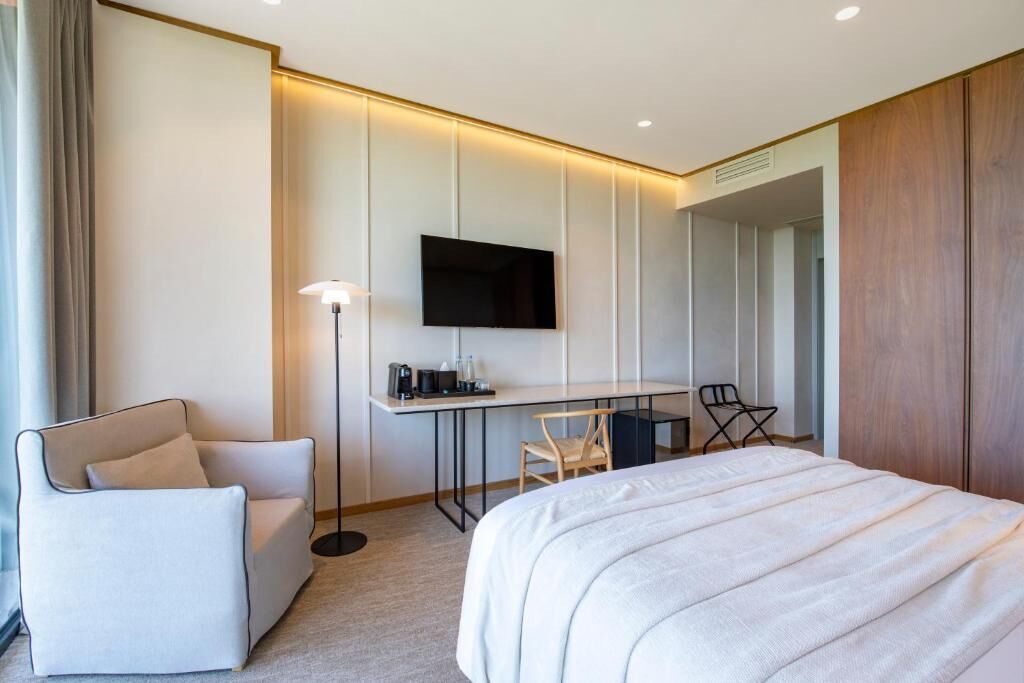 Una habitación de hotel moderna con una cama grande, un escritorio con televisor de pantalla plana, una silla y un sofá.