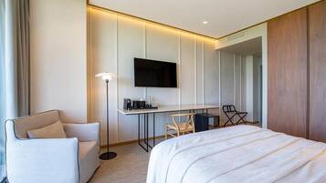 Una habitación de hotel moderna con una cama grande, un escritorio con televisor de pantalla plana, una silla y un sofá.