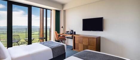 Habitación de hotel con dos camas, un escritorio, una silla y una televisión.