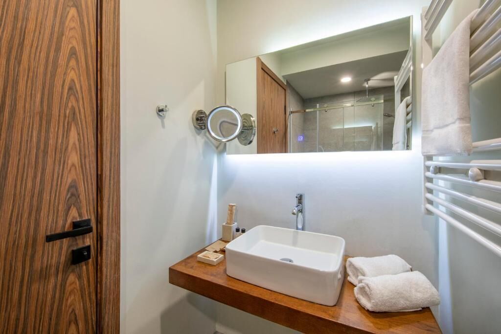 A bathroom with a wooden vanity, a white sink, and a mirror.