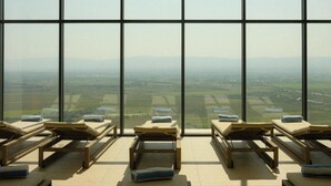 A sunlit room with large windows offering a view of a distant landscape. - Kvareli Lake Resort (Kvareli)