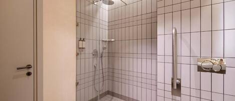 Un baño pequeño y moderno con cabina de ducha de vidrio, lavamanos blanco y un inodoro.