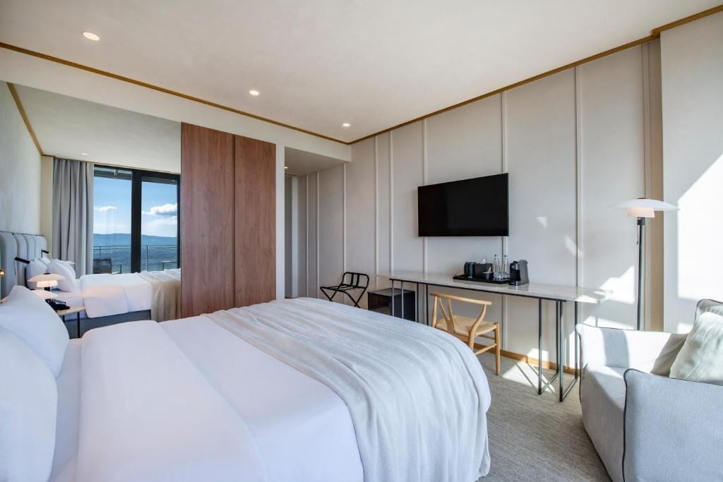 Une chambre d’hôtel moderne, dotée d’un grand lit, d’un bureau, d’une télévision et offrant une vue sur la ville.